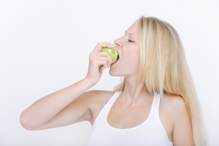 Young woman eating fruit against white background,close upの写真素材