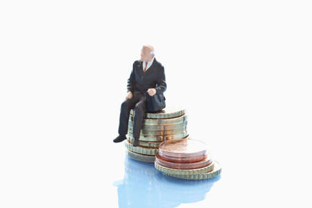 Businessman  figurine sitting on stack of euro coinsの写真素材