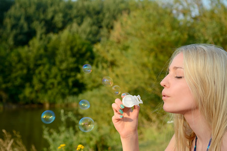 Blonde young woman making soap bubblesの写真素材