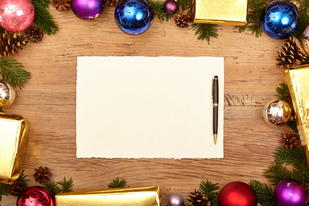 Christmas presents, fir twigs, baubles and blank card with ballpen on woodの写真素材