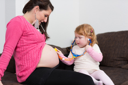 Mother and daughter playing with pregnant bellyの写真素材