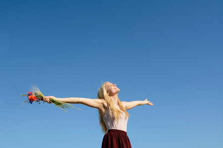 Beautiful young blonde woman holding bunch of flowersの写真素材