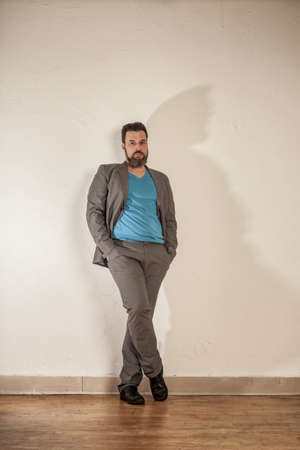 Relaxed business man with beard leaning on wallの写真素材