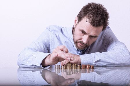 Business man counting money, stacks of coins on office deskの写真素材
