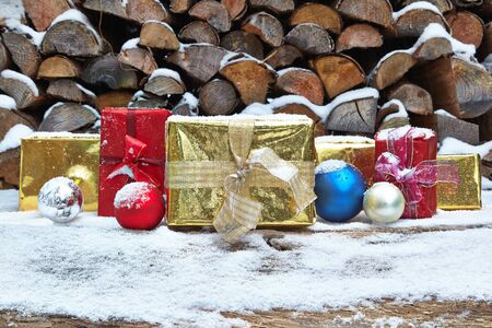 Christmas presents and baubles in front of woodpileの写真素材