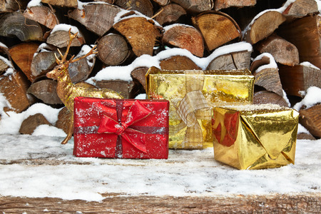 Christmas presents and deer figurine in front of woodpileの写真素材