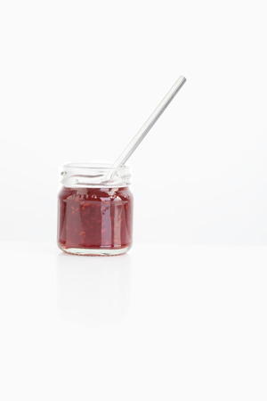 Spoon in raspberry jam jar on white backgroundの写真素材