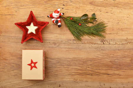 Christmas present, fir twig and Santa Claus figurine on woodの写真素材