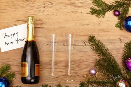 Champagne bottle, champagne glasses and fir twigs on woodの写真素材