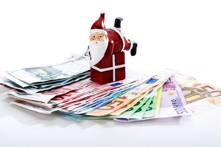 Santa Claus on gift lying on fanned euro notesの写真素材