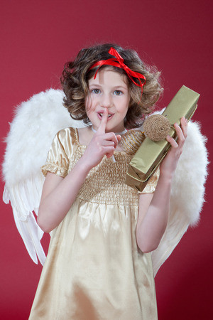 Girl holding gift with finger on lips,portraitの写真素材