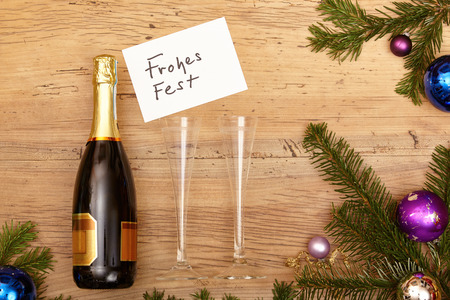 Champagne bottle, card Happy Holidays, champagne glasses and fir twigs on woodの写真素材