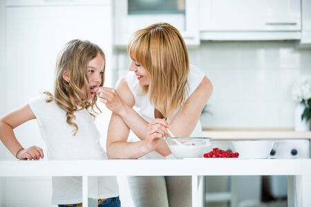 Mother and daughter preparing muesli with raspberriesの写真素材