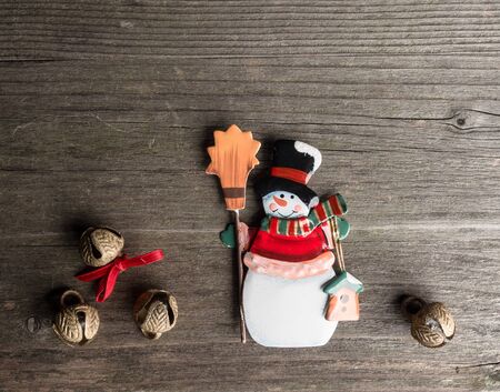 Christmas decoration of metal, snowman and bells on woodの写真素材