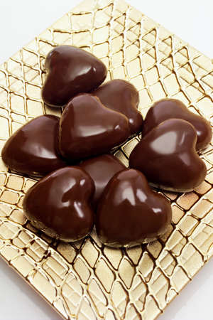 Chocolate pralines on golden plate, heart-shapedの写真素材