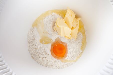 Mixing bowl with egg, butter and flourの写真素材