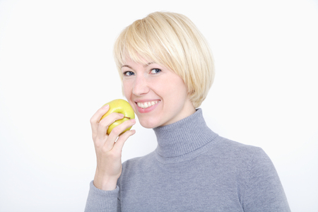 Close up of young woman eating fruit against white background,portrait,smilingの写真素材