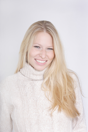 Young woman wearing turtleneck jumper against white background,portrait,smiling,close upの写真素材