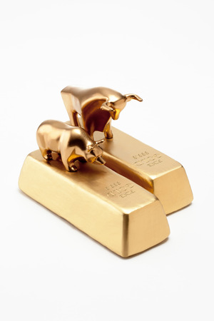 Golden bull and bear figurines on top of gold barsの写真素材