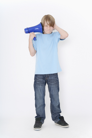 Germany,Bavaria,Ebenhausen,boy litsening to megaphone against white background,portraitの写真素材