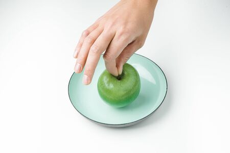 Hand holding green apple over plateの写真素材