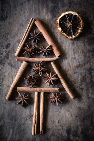 Christmas tree of cinnamon sticks and star anise on dark woodの写真素材
