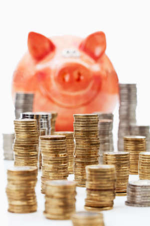 Piggy bank with piles of euro coins on white backgroundの写真素材