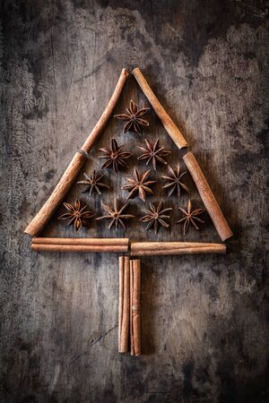 Christmas tree of cinnamon sticks and star anise on dark woodの写真素材