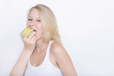 Young woman eating fruit against white background,portrait,close upの写真素材