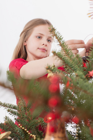 Girl positioning Christmas bauble on treeの写真素材