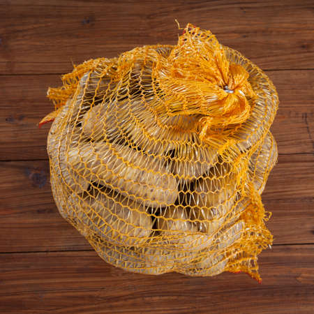 Potatoes in net on woodの写真素材