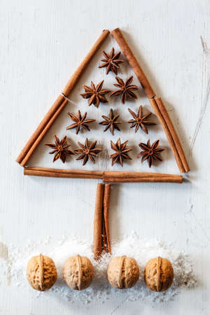 Christmas tree of cinnamon sticks, star anise and walnuts on white woodの写真素材