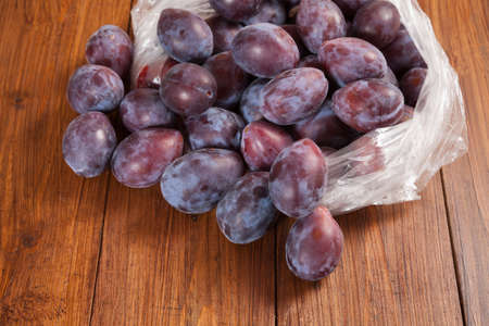 Plastic bag with plums on woodの写真素材