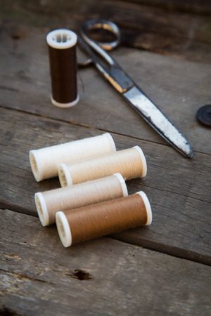 Scissors, buttons and sewing silk on woodの写真素材