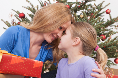 Mother and daughter with touching head, Christmas tree in backgroundの写真素材