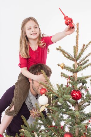 Girl sitting on man's shoulders and positioning tree topperの写真素材
