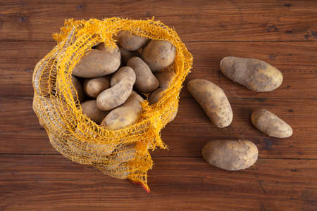 Potatoes in net on woodの写真素材