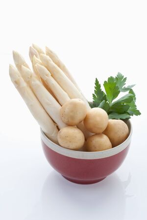 Asparagus,potatoes and parsley in bowl on white backgroundの写真素材
