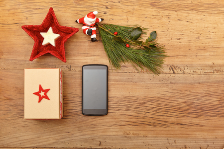 Christmas present, mobile phone, fir twig and Santa Claus figurine on woodの写真素材