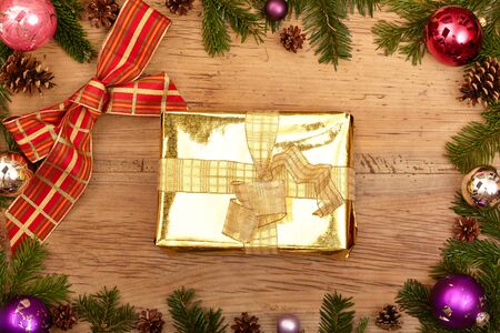 Christmas present, ribbon, fir twigs and baubles on woodの写真素材