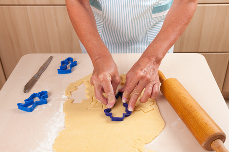 Woman cutting out dough, rolling pin, dough, flour and pastry cuttersの写真素材