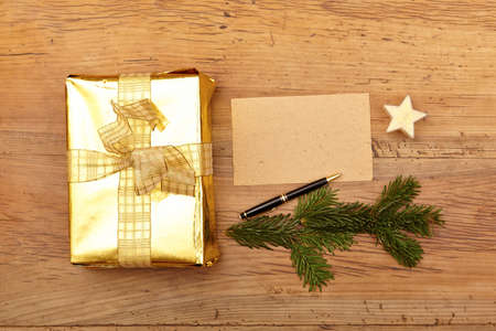 Golden christmas present and blank card on woodの写真素材
