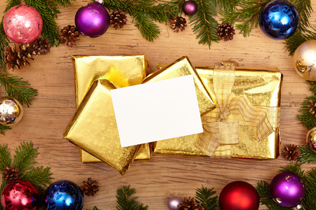 Christmas presents, fir twigs, baubles and blank card on woodの写真素材