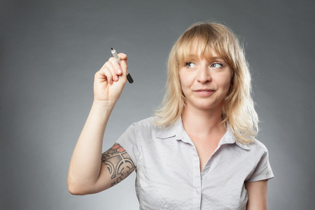 Young woman portrait on grey background, writing with markerの写真素材