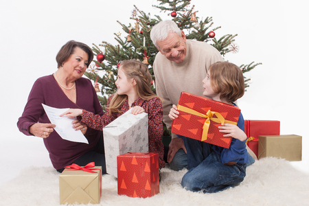 Grandparents with grandchild sitting with Christmas gift, smilingの写真素材