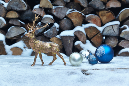 Deer figurine and baubles in snow, woodpileの写真素材