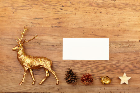 Christmas decoration, deer figure, blank card and cones on woodの写真素材