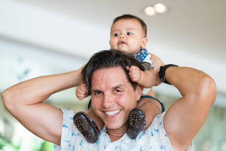 Multi ethnic family, Father carrying baby son on shouldersの写真素材