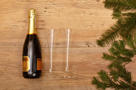 Champagne bottle, champagne glasses and fir twigs on woodの写真素材
