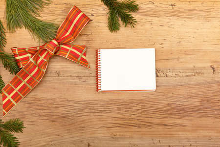 Blank notepad, fir twigs and ribbon on woodの写真素材